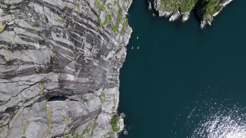 Sun reflects off water near craggy cliff