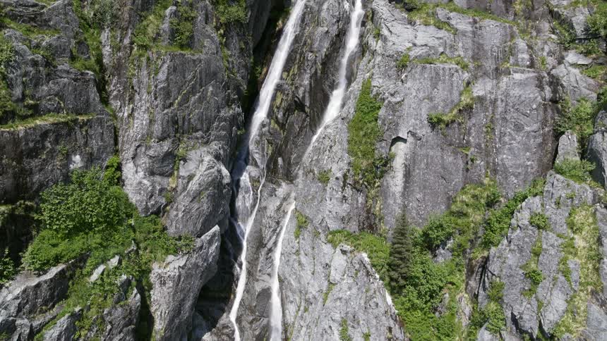 A pair of thin waterfalls down the side of a sheer stone mountain