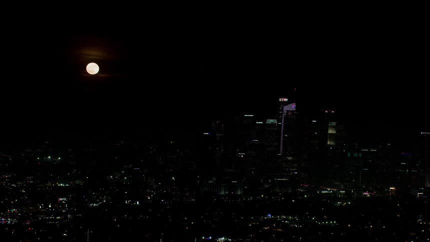 The moon is high above the city at night