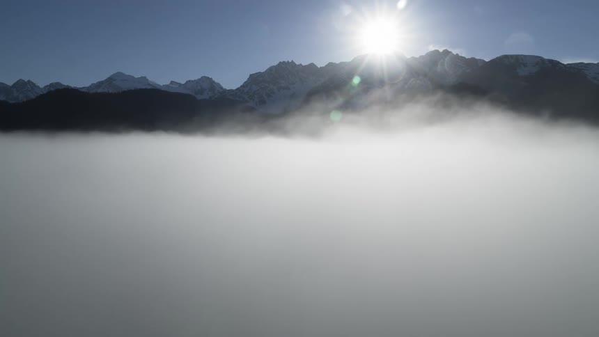 A mountain range peaking up through thick fog during the day