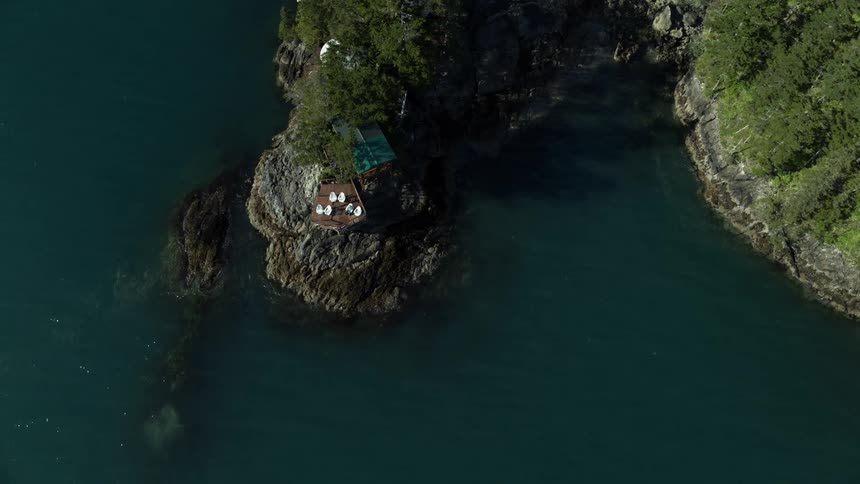 Remote resort cabin on small rocky island in deep blue lake
