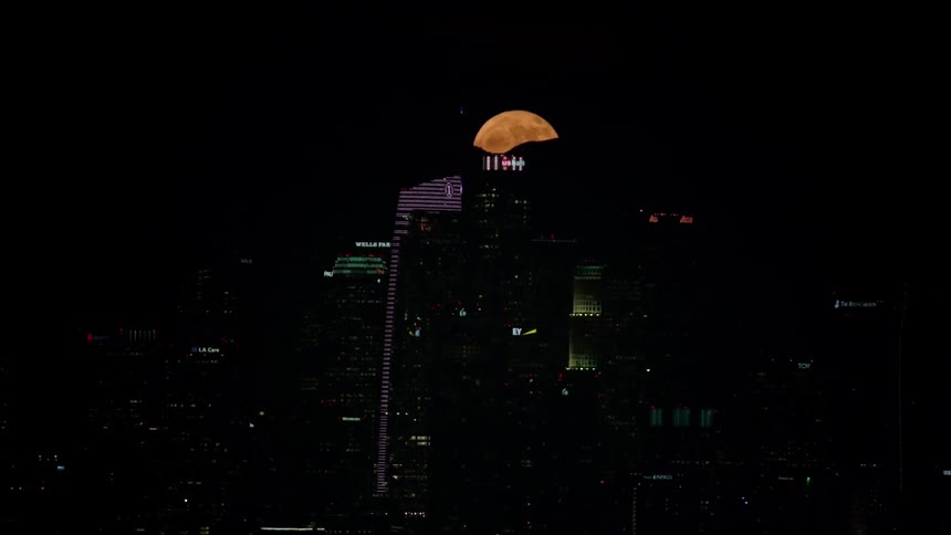 A city skyline at night with the sky and the moon in the background