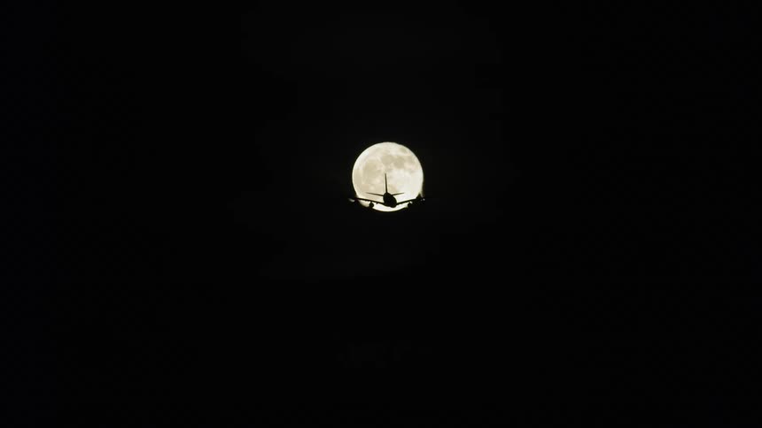 Airplanes is cast into a silhouette by the moon at night