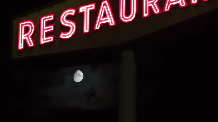A neon restaurant sign is lit up under moonlight