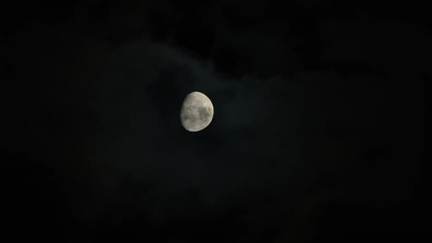 The moon in the night sky with clouds floating by