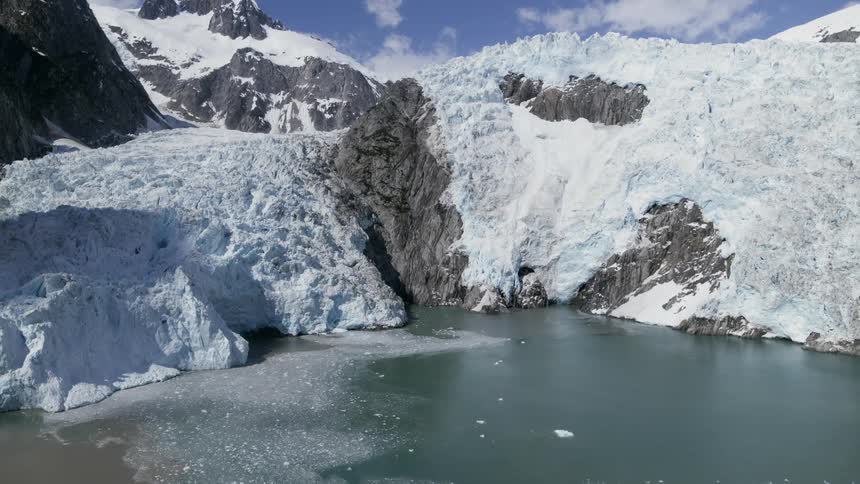 A mountain ridge with ice and snow with a frozen lake at the bottom