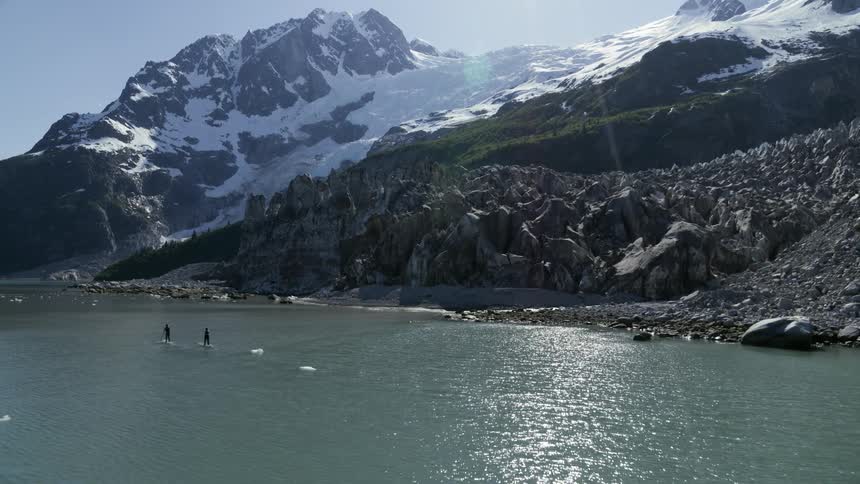 Two people paddleboard near the mountain