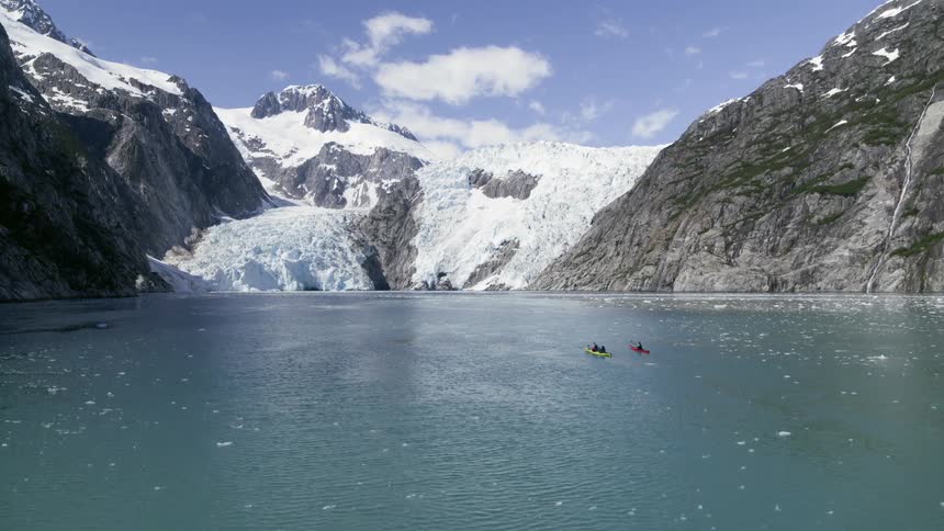 People canoe in a lake by the mountains