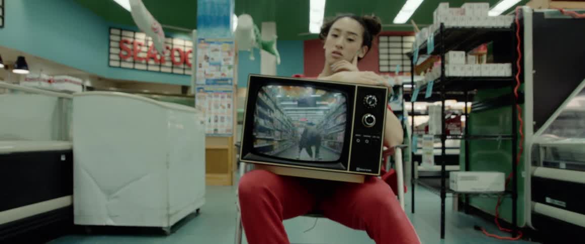 A woman hunched over in a grocery store aisle is displayed on a television