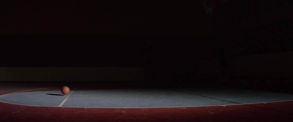 Basketball bouncing out from the shadows on basketball court
