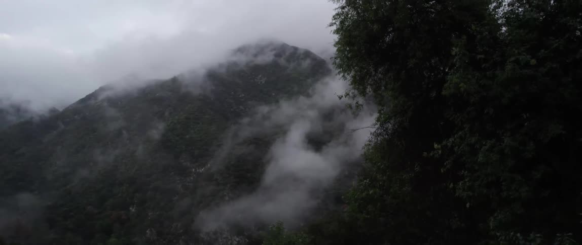 Misty clouds hang near the top of mountains