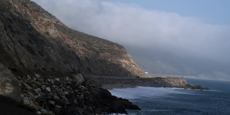 Vehicles drive near the coast on a cloudy day