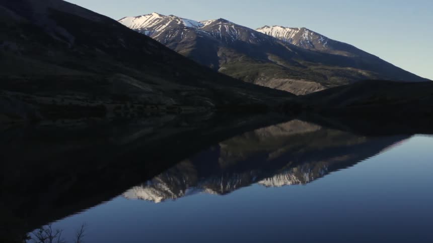 Mountains reflect on a calm lake on a clear day