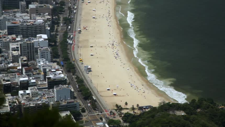 Waves roll into a beach next to a city