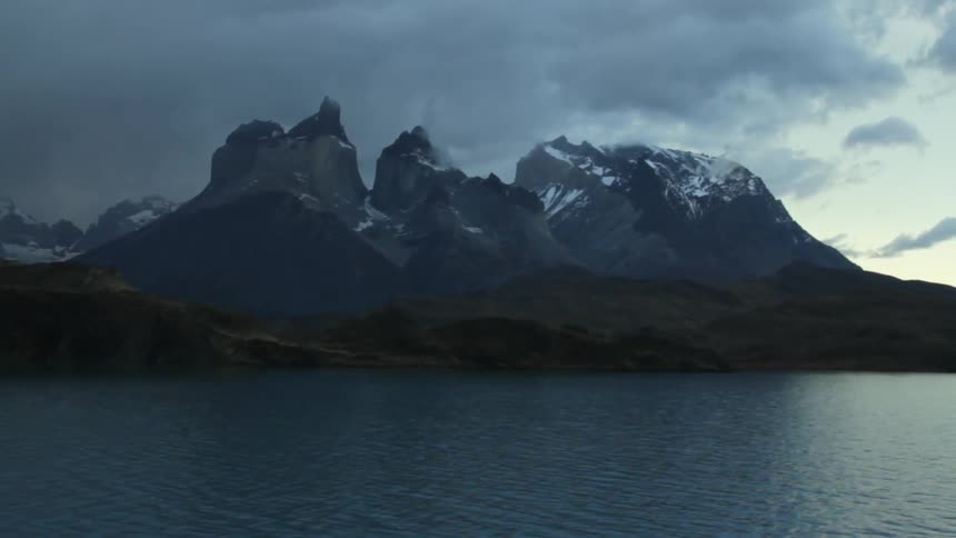 A lake near a snow covered mountain on a overcast day