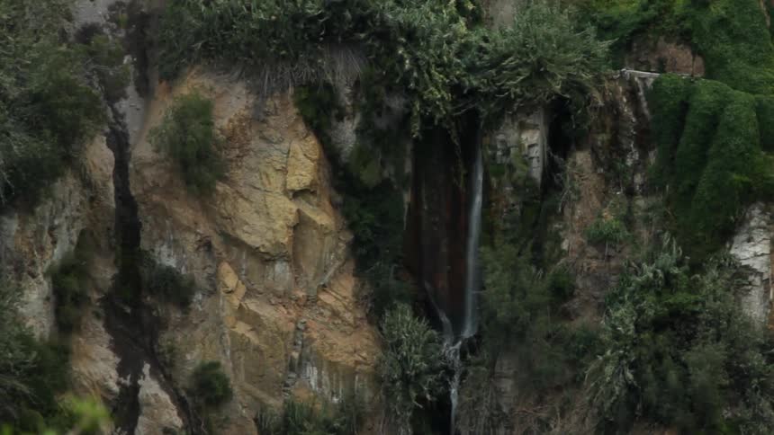 Water flows over a rocky cliff in the wilderness