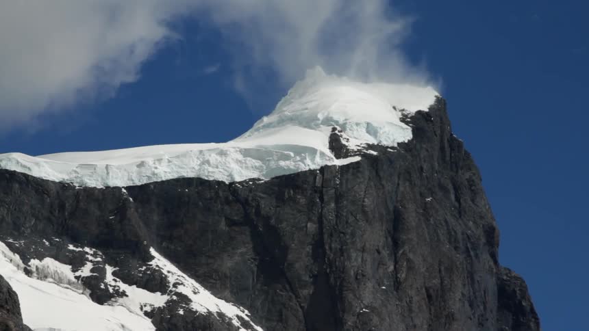 Clouds lifting away from a snow-capped mountain peak