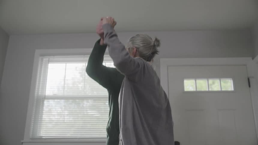 Elderly man and woman dance at home