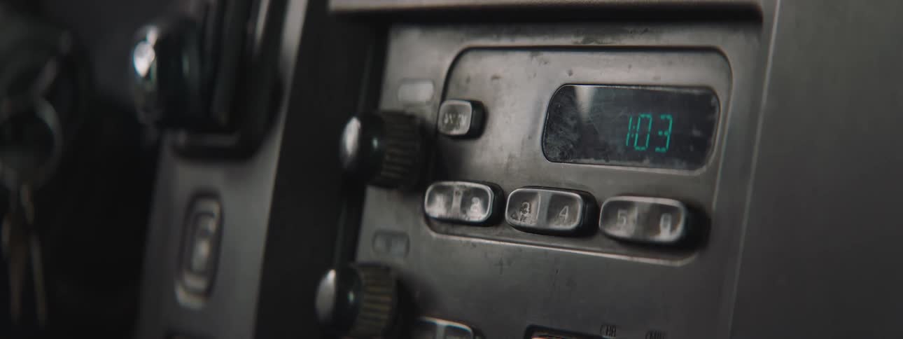 A man changes a station on a radio in a car