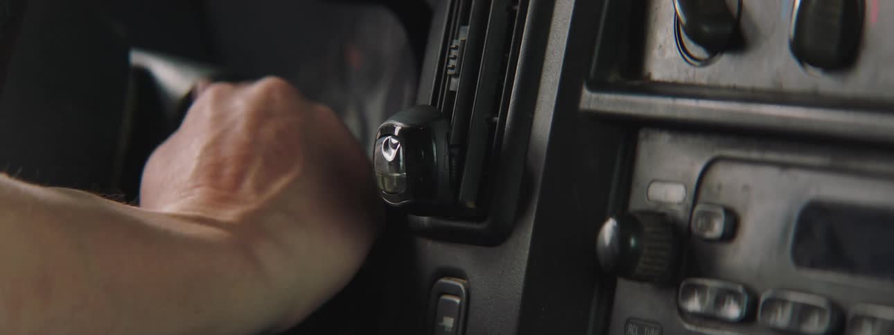 Man turns ignition switch on car and turns on the radio on the dashboard