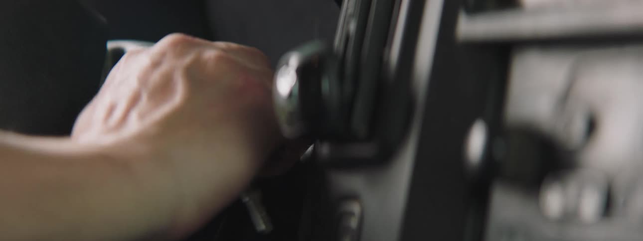 A hand puts the key in the ignition and turns it