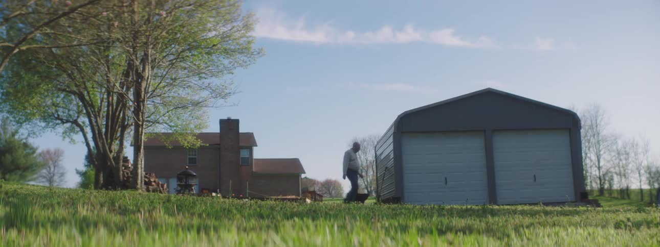 Male walks through the backyard towards the two car garage opens the door on the left and walks into the garage