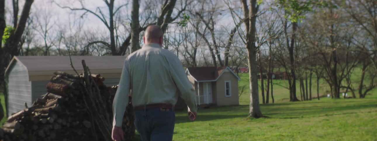 Elderly man walks on the green grass in the yard