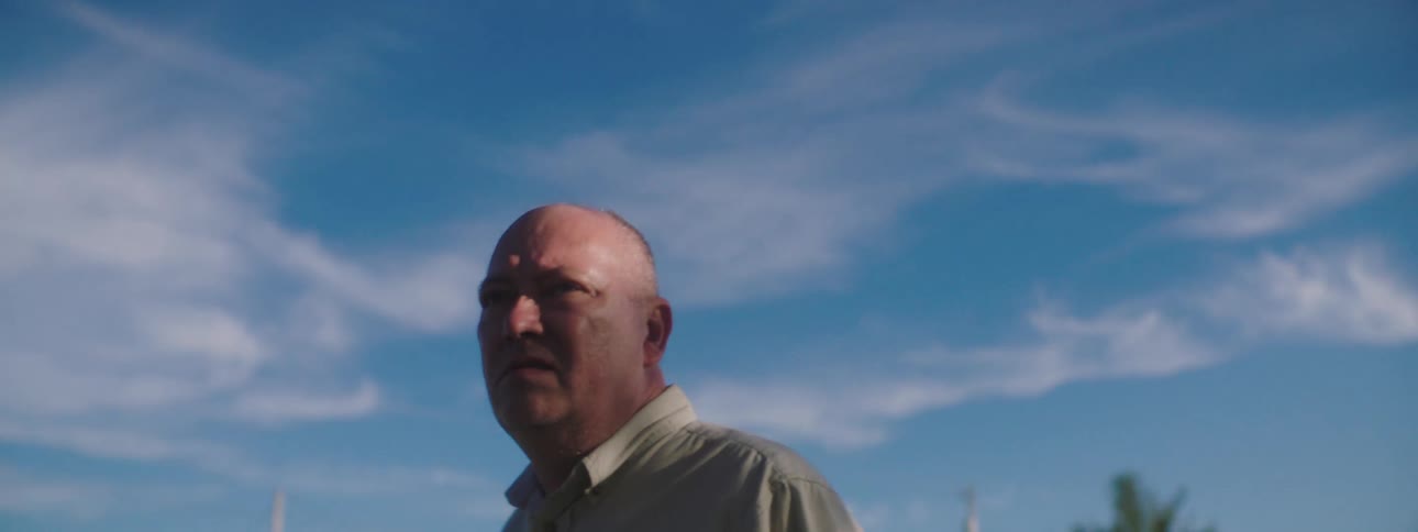 An older man looks around confused while standing near a house