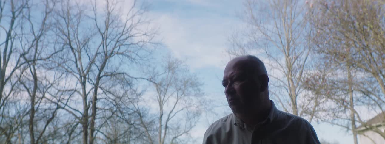 A middle aged man opening a garage while lost in thought