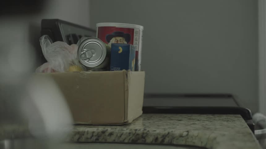 A man and woman put groceries and a bag with a heart on a counter