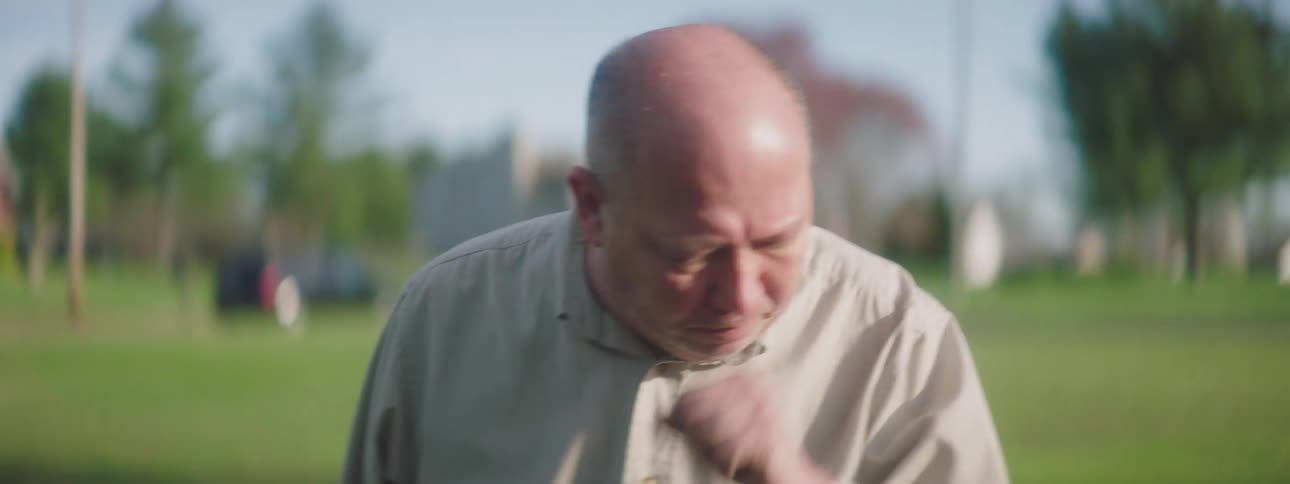 A man walks along and coughs in to his hand