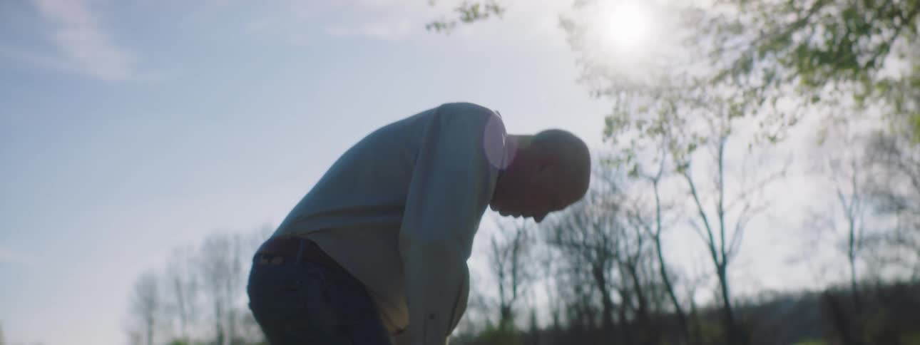 A man coughs and grabs his chest and bends over