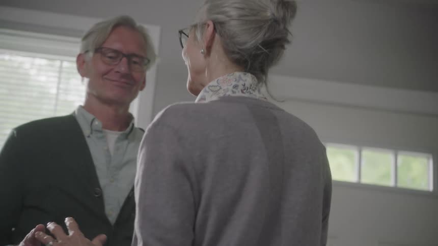 An elderly man and woman dance together