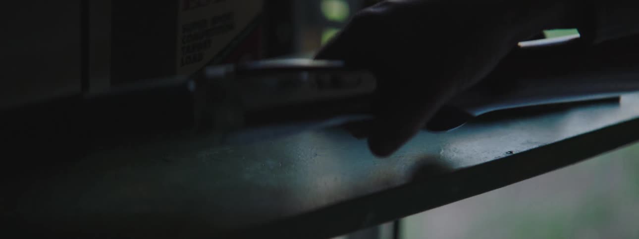 A man caresses a shotgun on a shelf in his garage before picking it up