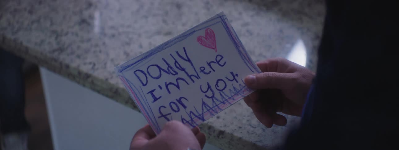 Girl wearing sweater gives a card to her dad