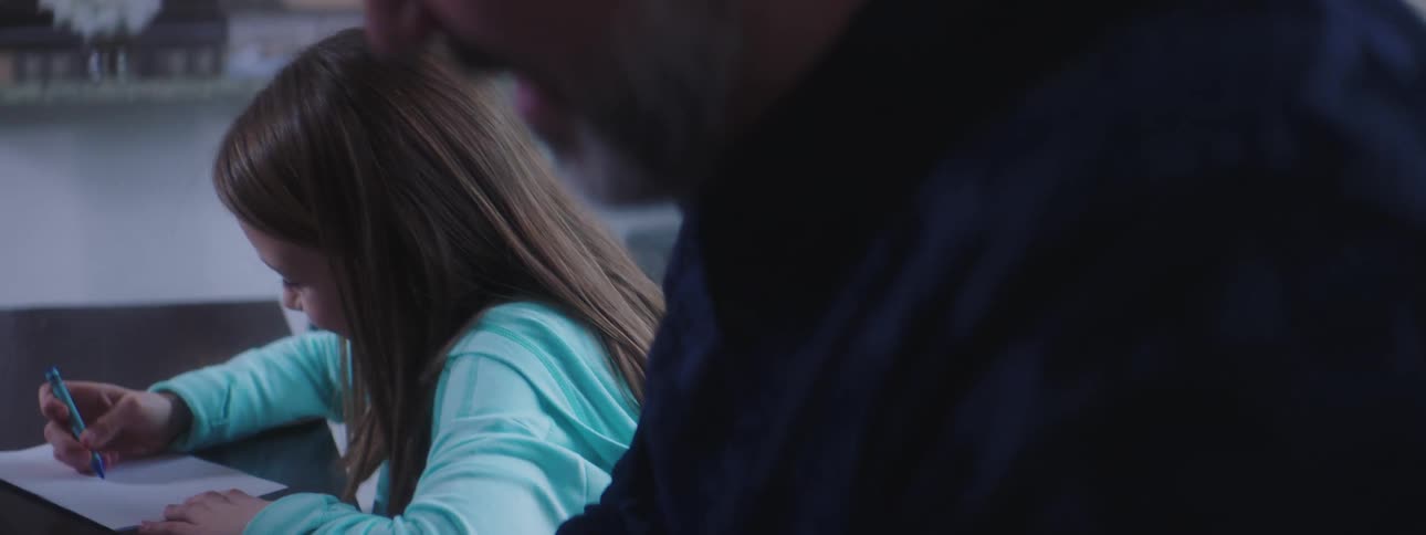 A young girl and a man sit and color together