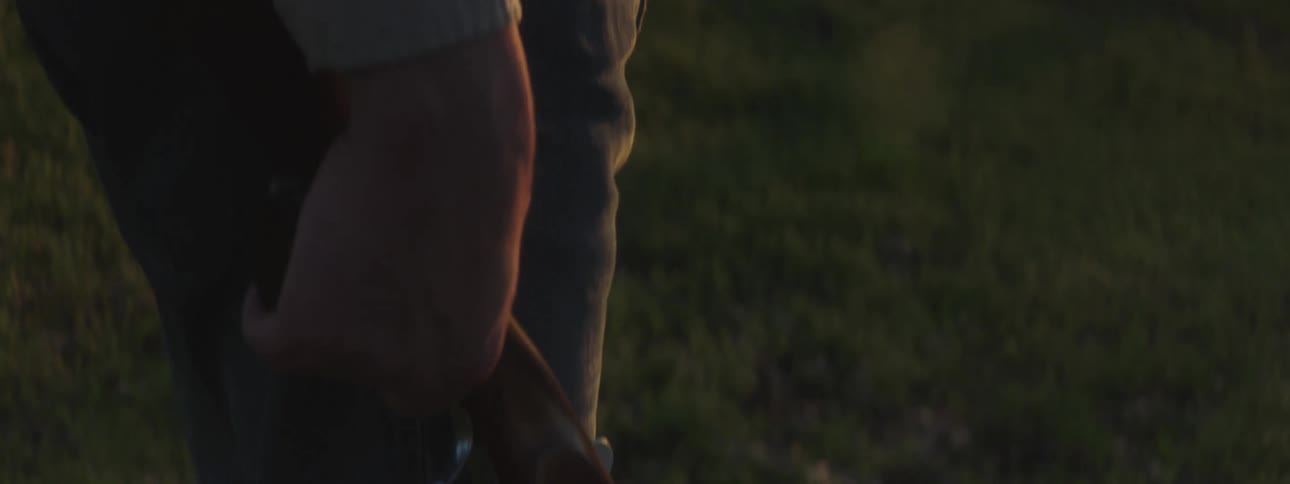 A man holding a gun talks on a cell phone