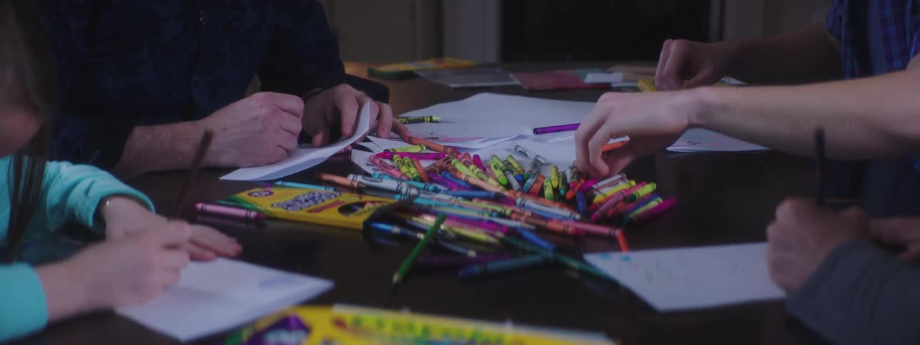 Pile of crayons on a table as people gathered around create cards
