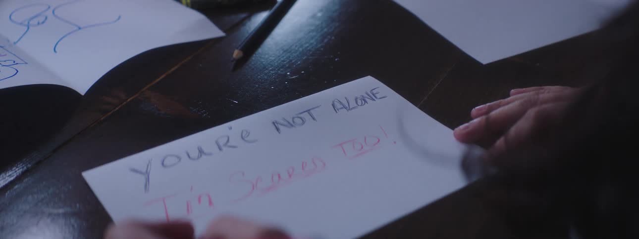 Woman sitting at the table writes a supportive letter at home