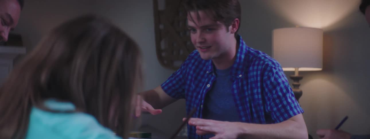 A teen aged boy talking to his younger sister and father