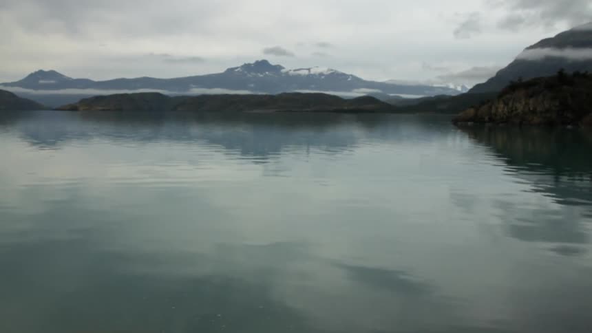 A lake near a snow covered mountain on a overcast day