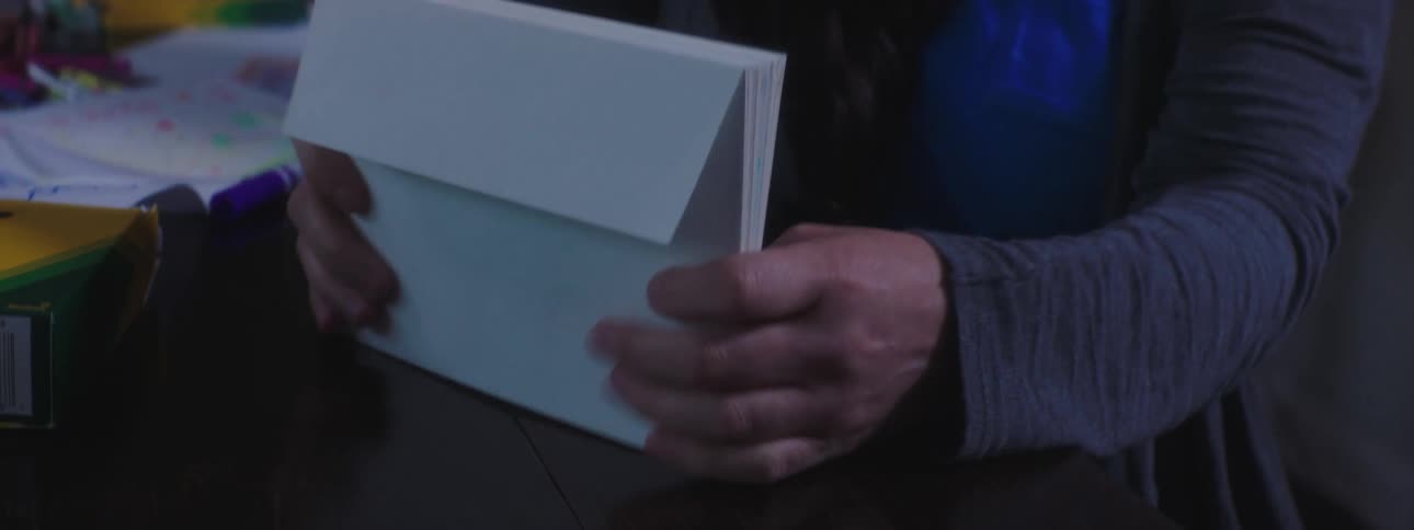 A mother hands her daughter a stack of envelopes