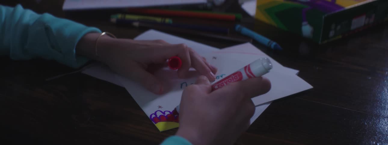 A girl uses a marker and colors a piece of paper