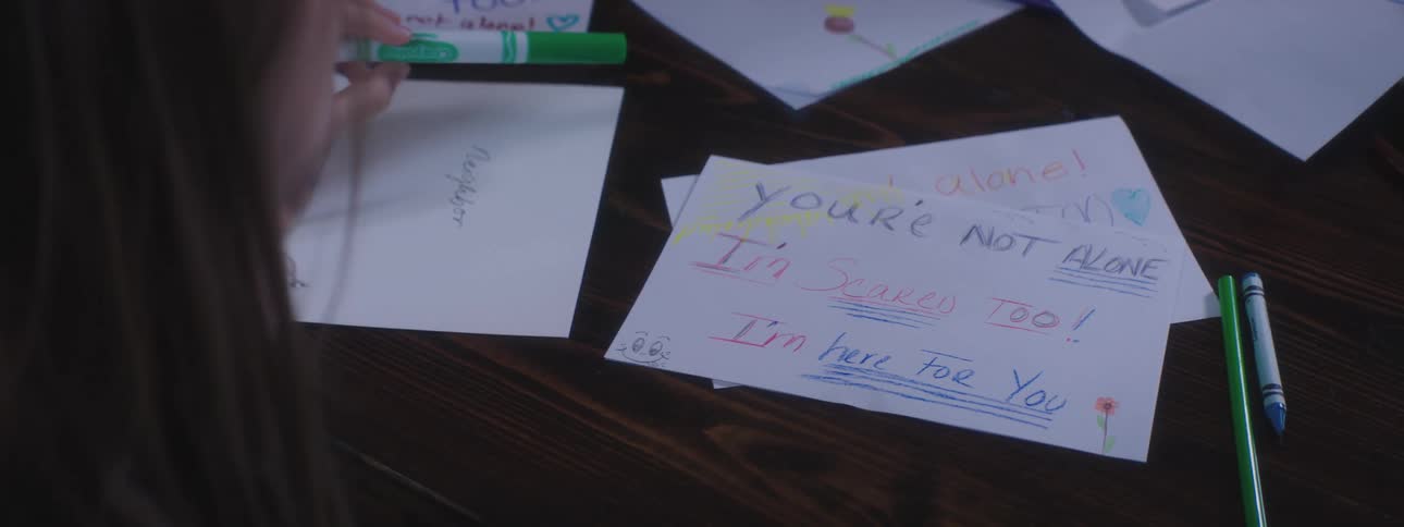 A girl finishes up drawing a sympathy card with a color pencil