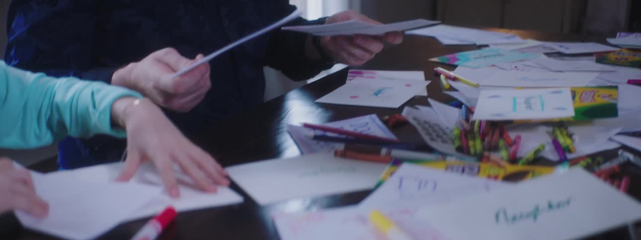 An adult and young girl sort paper as they do crafts