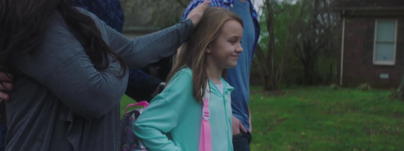 A family walks by houses looking happy while the mother strokes her daughters hair
