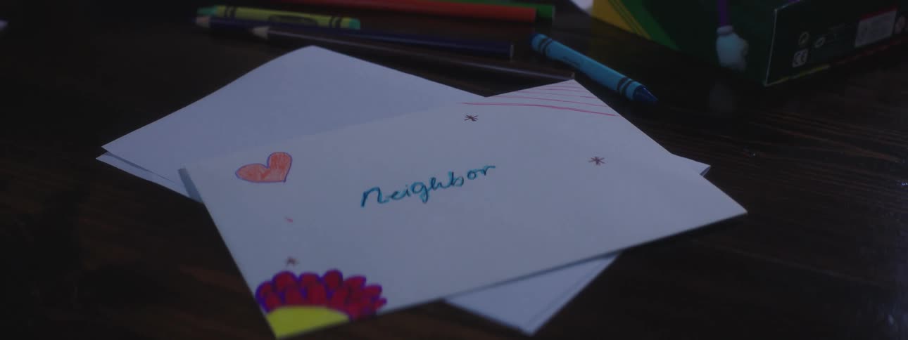 Person picks up note drawn on with crayons and addressed to the neighbor