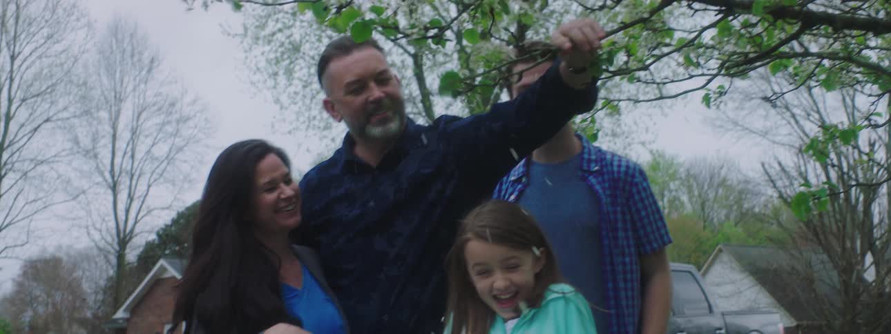 A family laugh as their daughter gets flower petals in her hair
