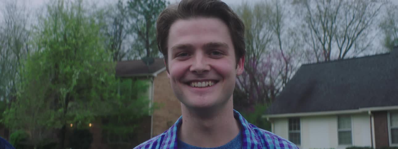 A man smiles and then laughs as a person taps his chin