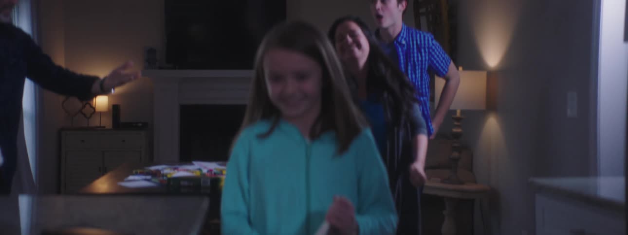 A family sits at a table and the mom then hands her daughter a stack of cards and they get up and walk away